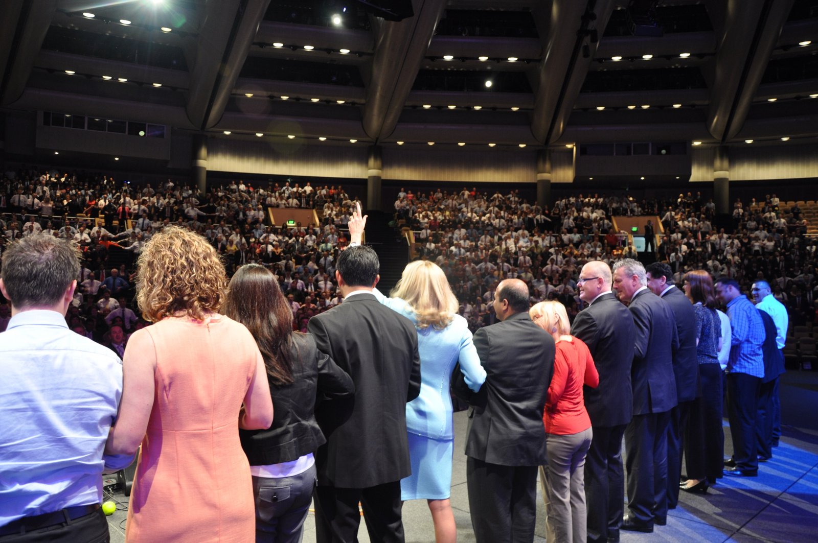 Lisa on stage with participants in front of a large arena audience
